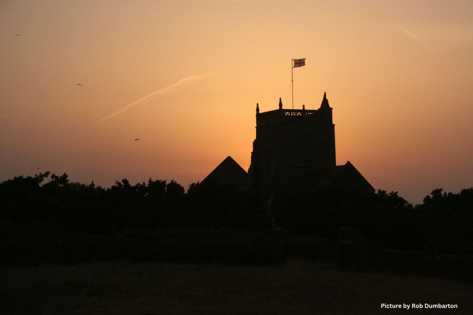 The silhouette of Uphill Church set against a golden sunset